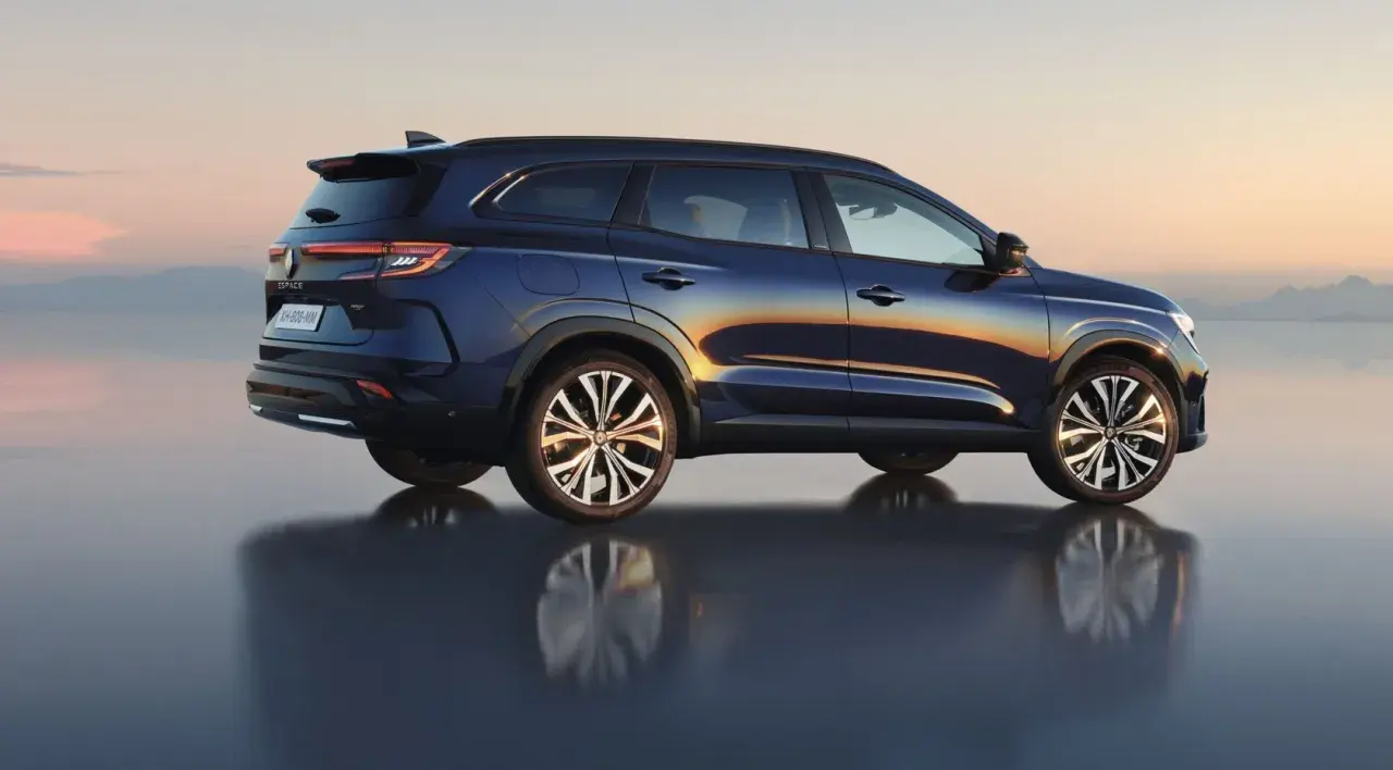 Granatowy Renault Espace 2024 z odbiciem na wodzie, na tle zachodzącego słońca.