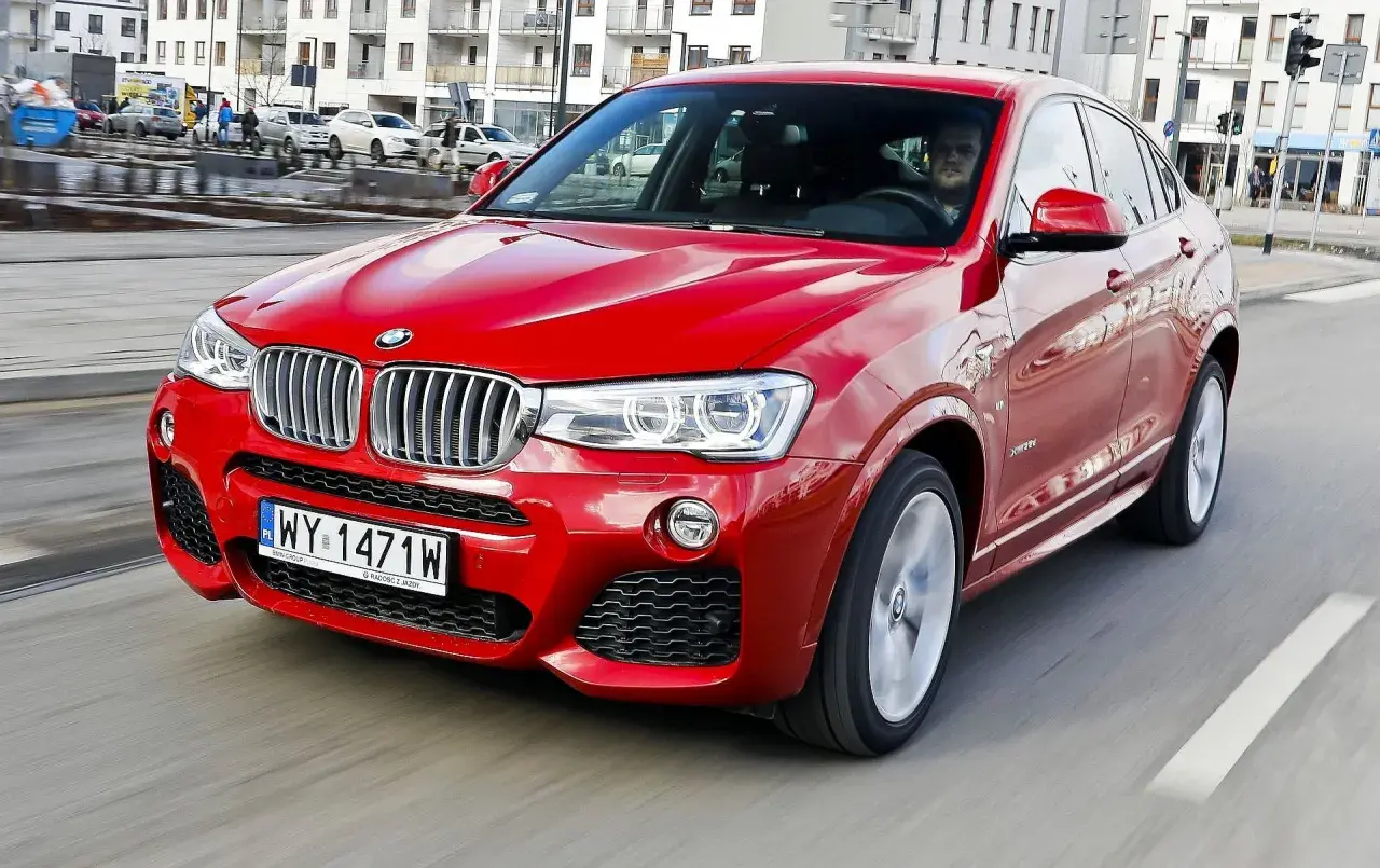 Czerwone BMW X4 2025 pędzi ulicą, błyszcząc w słońcu. Kierowca w środku, gotowy na przygodę.