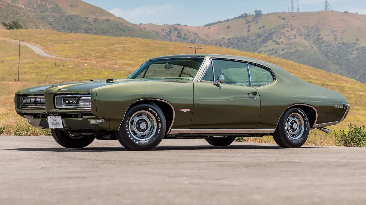 Zielony Pontiac GTO z 1969 roku na tle wzgórz. Klasyk amerykańskiej motoryzacji.