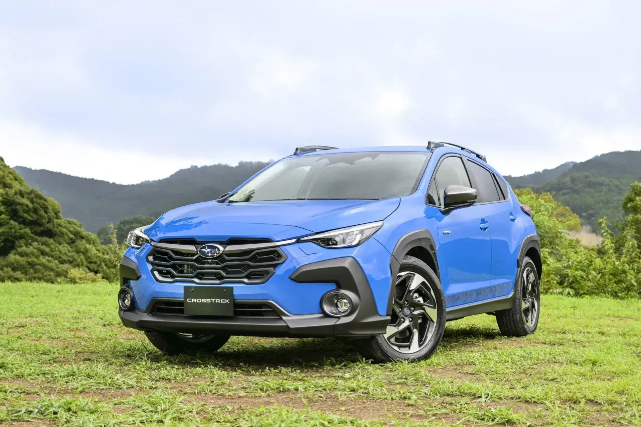Niebieski Subaru XV Crosstrek na tle zielonych wzgórz. Gotowy na przygodę w terenie.