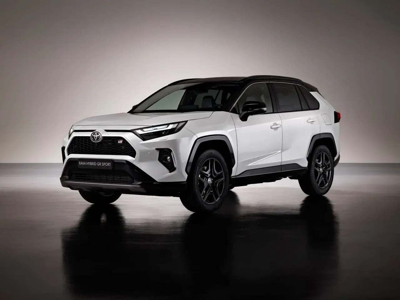 Biały Toyota RAV4 Hybrid GR Sport 2023 z czarnym dachem i felgami, prezentujący sportowy design.