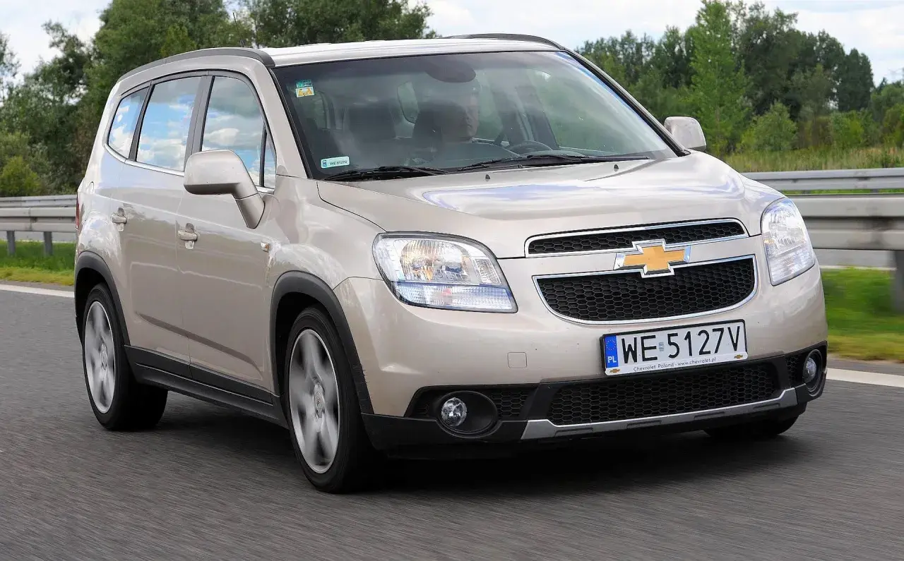 Złoty Chevrolet Orlando na drodze. Kierowca w środku, widok z przodu. Wiele osób szuka chevrolet orlando opinie przed zakupem.