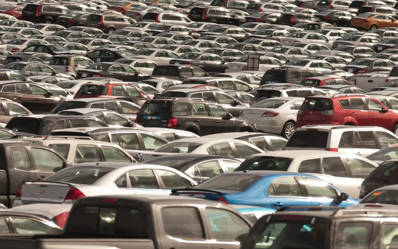 Ogromny parking pełen samochodów różnych marek. Widać wiele modeli, od sedanów po SUV-y, w różnych kolorach.