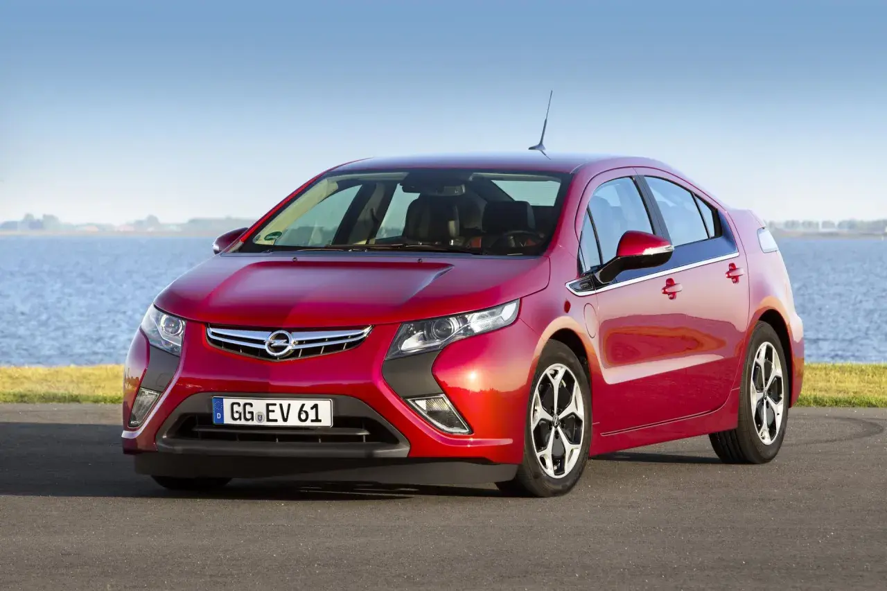 Czerwony Opel Ampera stoi nad jeziorem, gotowy na ekologiczną podróż.