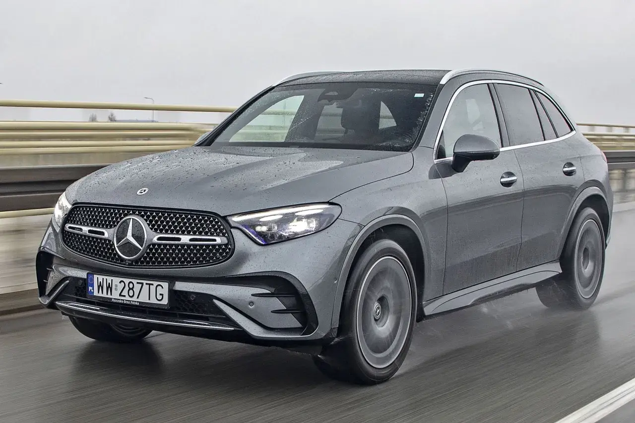 Szary Mercedes-Benz GLC jedzie po mokrej drodze.
