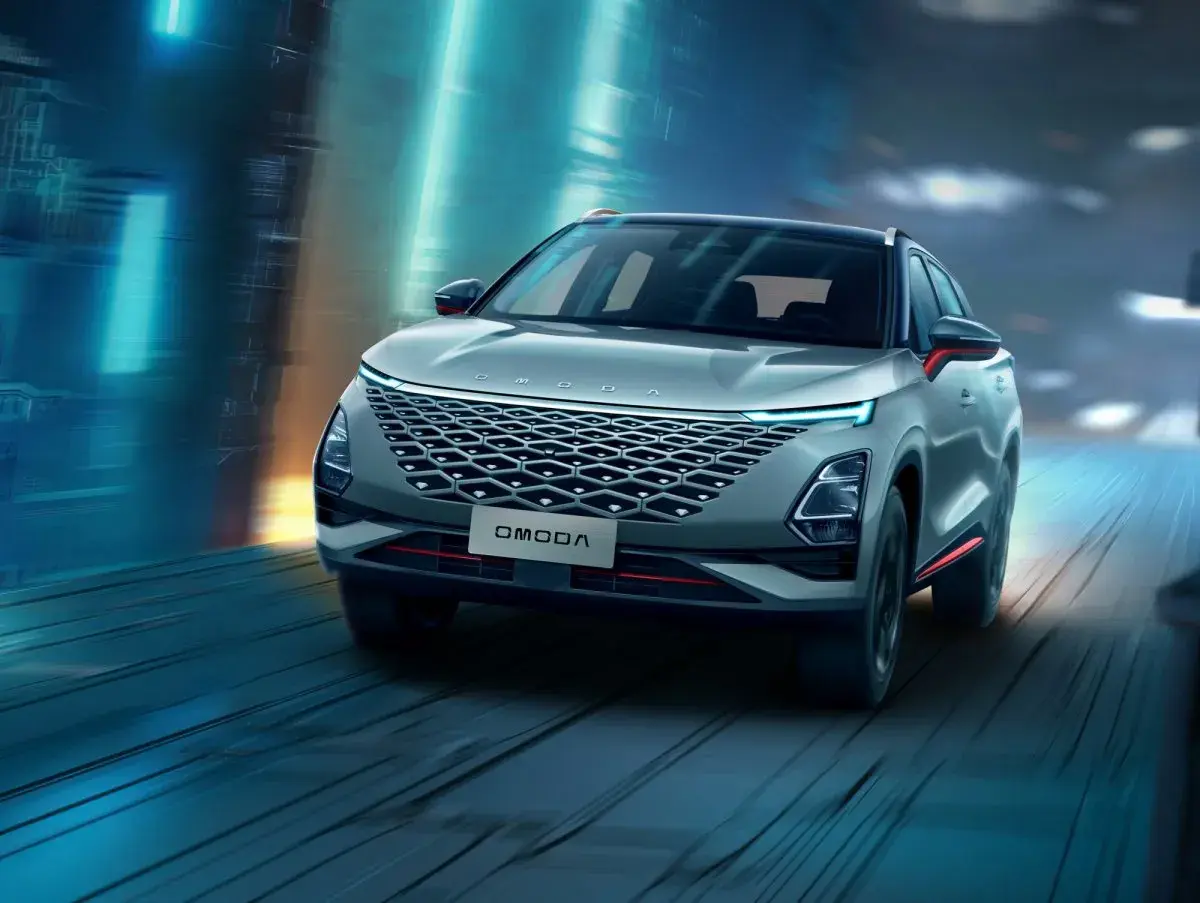 Nowoczesny SUV OMODA pędzi nocą przez futurystyczne miasto. Omoda co to za marka? To styl i innowacja.