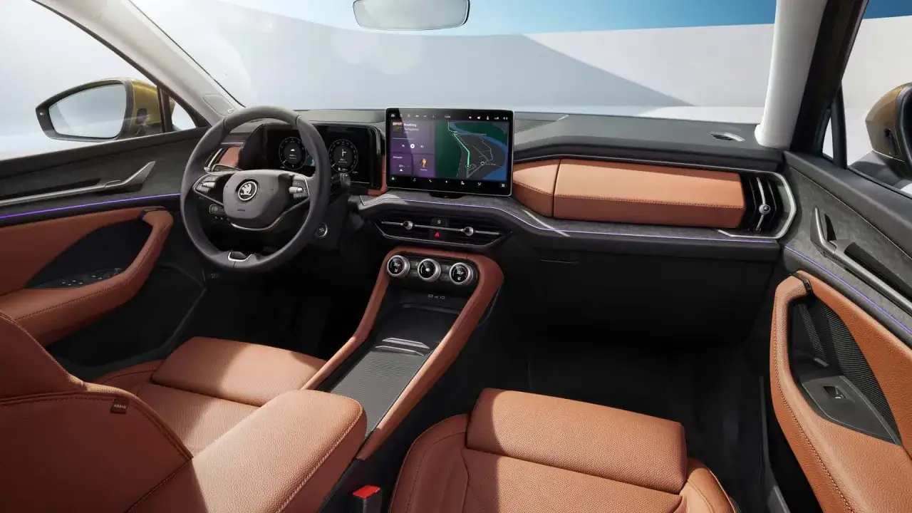 Wnętrze Skoda Kodiaq 2025 z brązową skórzaną tapicerką, dużym ekranem multimediów i nowoczesnym panelem sterowania.