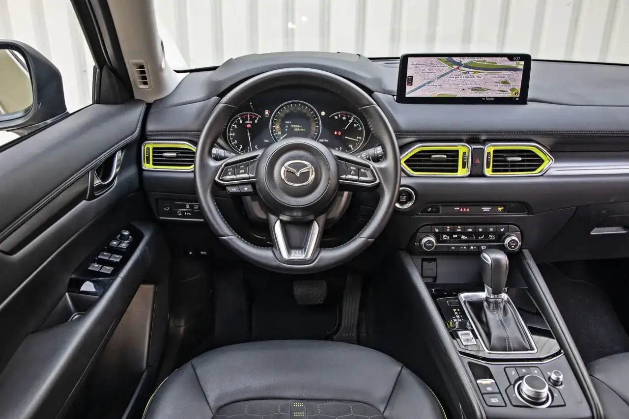 Wnętrze Mazdy CX-5 z żółtymi akcentami. Kierownica, nawigacja i panel sterowania. Sprawdź mazda cx-5 cena!