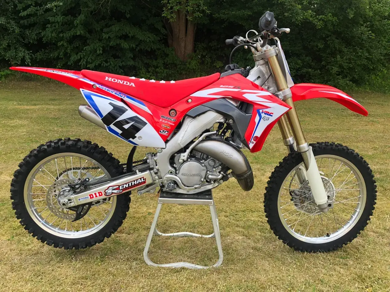 Czerwony motocykl crossowy Honda CR 125 z numerem 14. Zastanawiasz się, honda cr 125 ile koni ma pod maską?