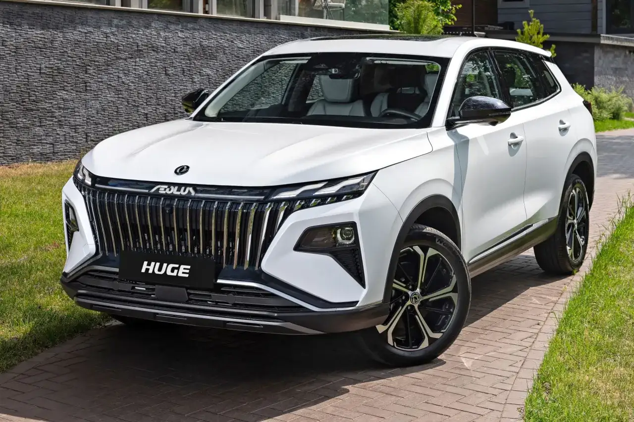 Biały, chinski suv premium z imponującym grillem i nowoczesnymi światłami, zaparkowany na podjeździe z kostki brukowej.