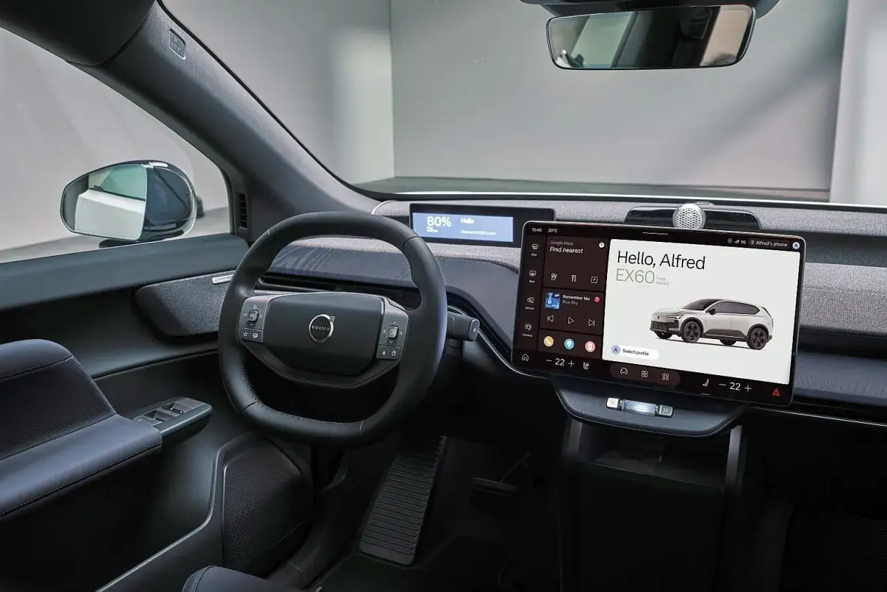 Wnętrze nowoczesnego Volvo EX60 z dużym ekranem dotykowym, cyfrowymi zegarami i kierownicą.