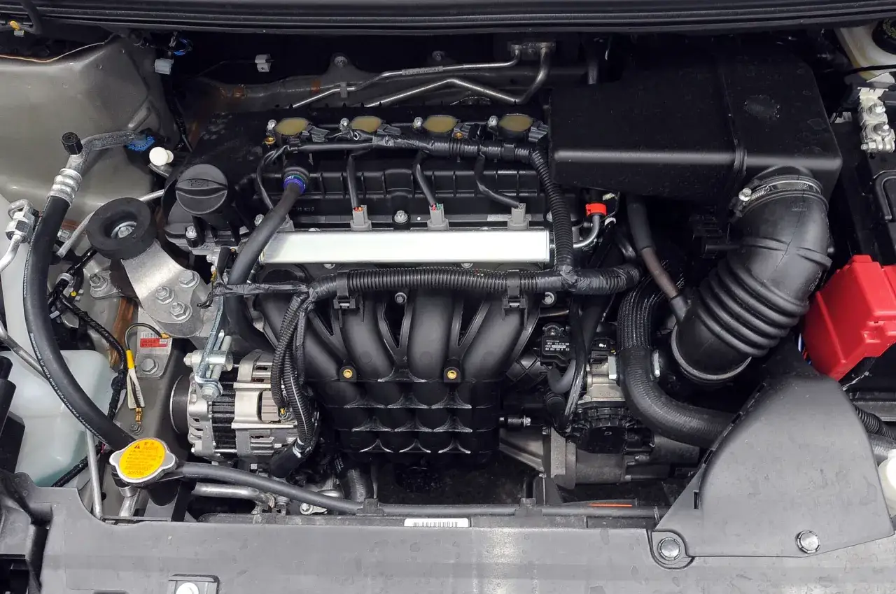 Silnik Mitsubishi Colt z widocznymi cewkami zapłonowymi, kolektorem dolotowym i alternatorem.