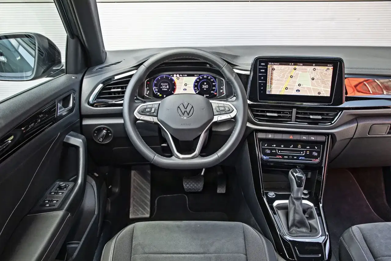 Wnętrze Volkswagena T-Roc: cyfrowe zegary, ekran nawigacji i panel klimatyzacji. Sprawdź aktualną volkswagen t-roc cena.