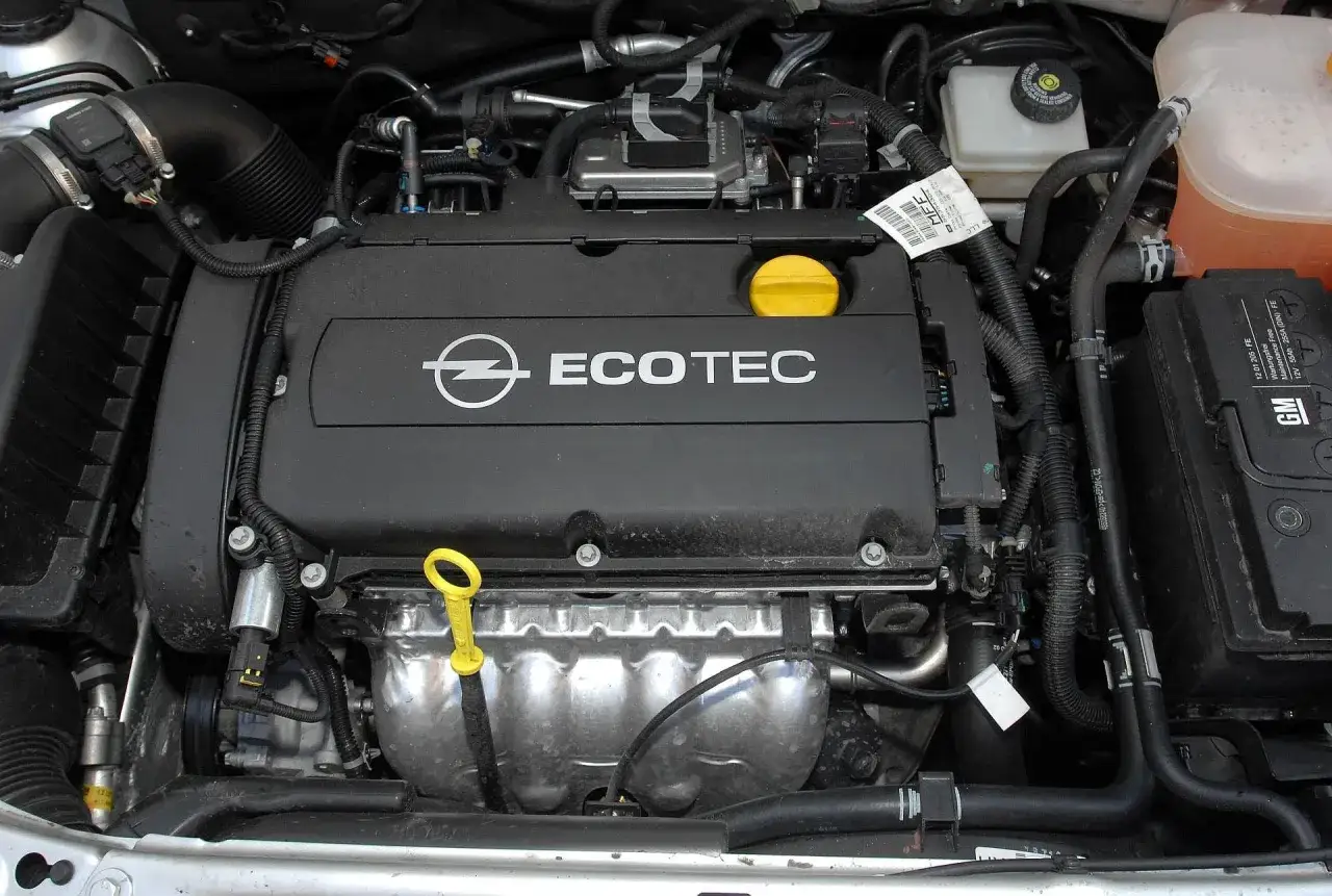 Silnik Ecotec w Opel Astra H 1.6 benzyna. Widoczny jest czarny kolektor, żółta miarka oleju i akumulator GM.