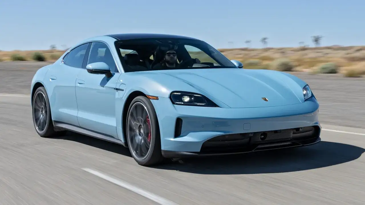 Błękitny Porsche Taycan jedzie po pustynnej drodze. Sprawdź aktualną porsche taycan cena i dowiedz się więcej o tym elektrycznym aucie.