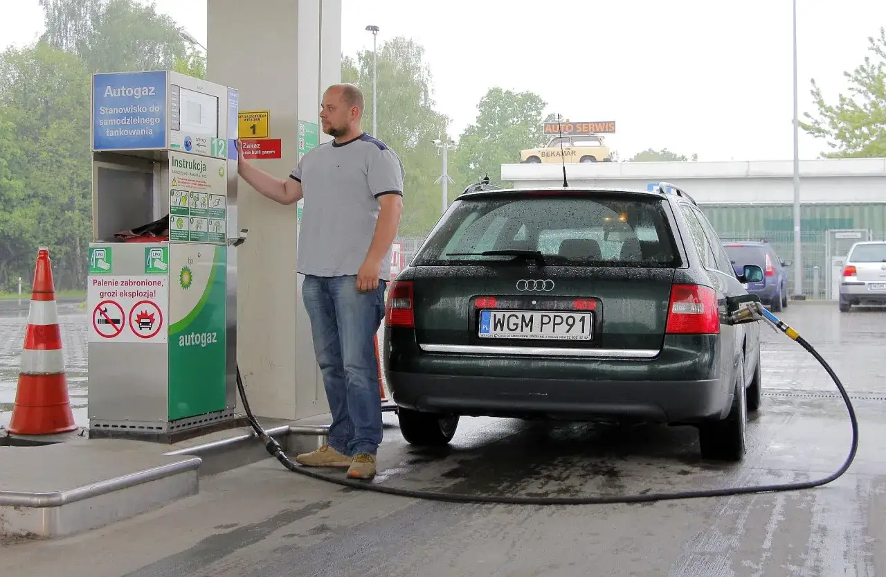 Mężczyzna tankuje gaz LPG do samochodu. Aktualna cena gazu lpg jest widoczna na dystrybutorze.