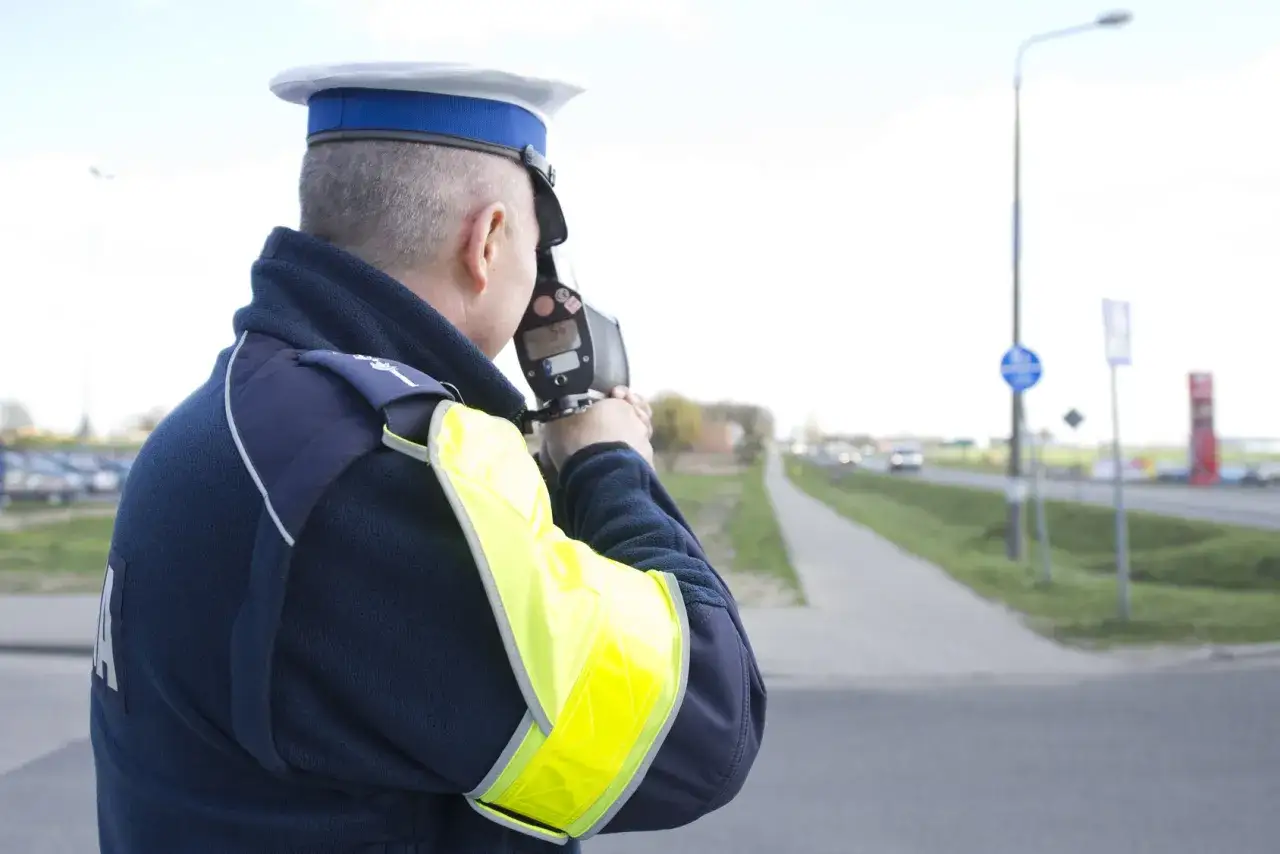 Policjant mierzy prędkość pojazdów. Może to być część jego pracy, a niekoniecznie kurs reedukacyjny.