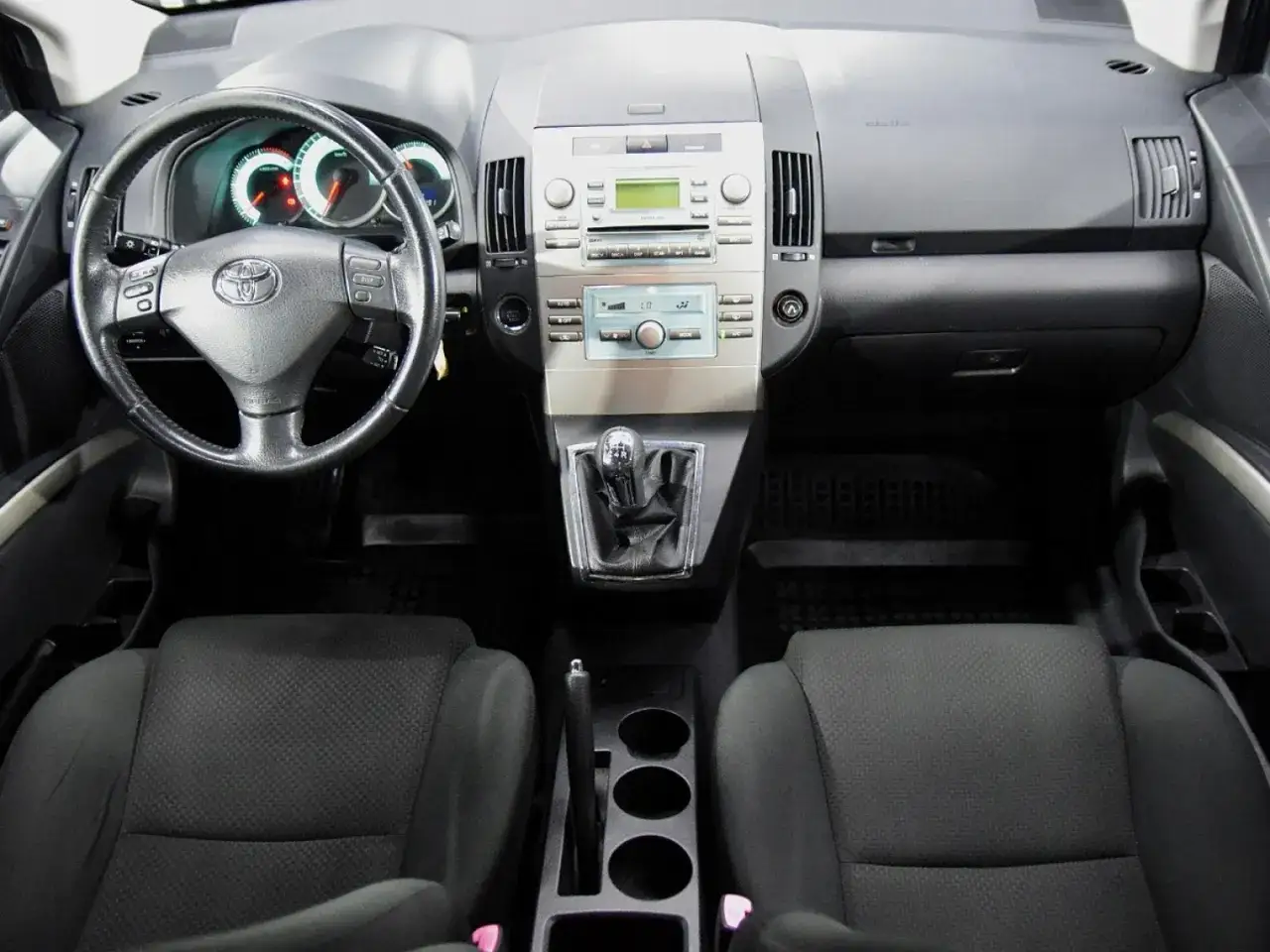 Wnętrze Toyoty Corolla Verso: kierownica, deska rozdzielcza z radiem i nawiewami, dźwignia zmiany biegów, fotele.