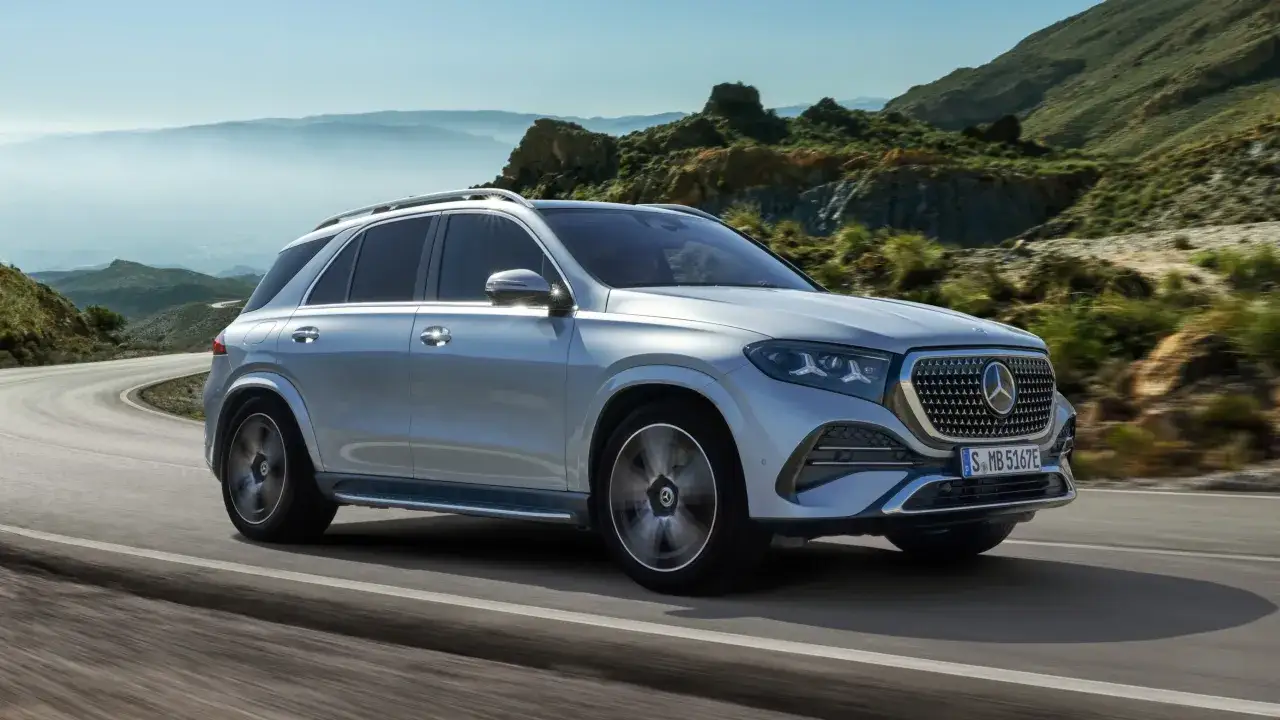 Srebrny Mercedes GLE 2026 pokonuje kręty górski trakt, ukazując swoją elegancję na tle malowniczego krajobrazu.
