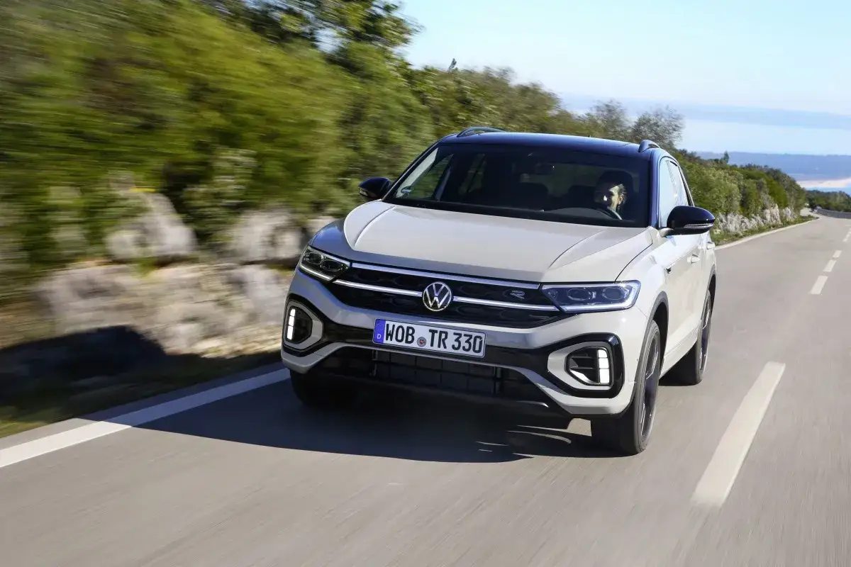 Jasnoszary Volkswagen T-Roc R na krętej drodze. Nawet z potencjalnymi usterkami, ten SUV prezentuje się dynamicznie.
