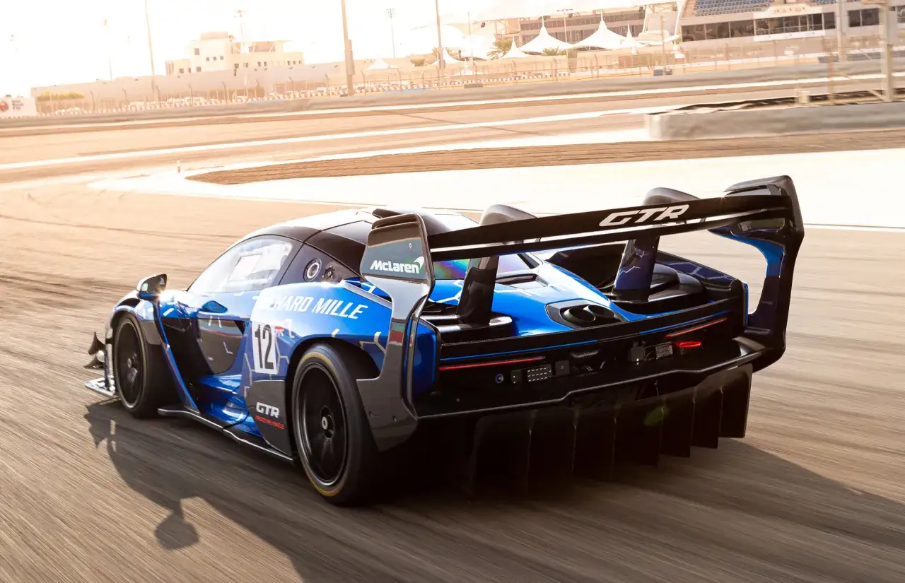 Niebieski McLaren Senna GTR z numerem 12 pędzi po torze wyścigowym, zostawiając za sobą smugę.
