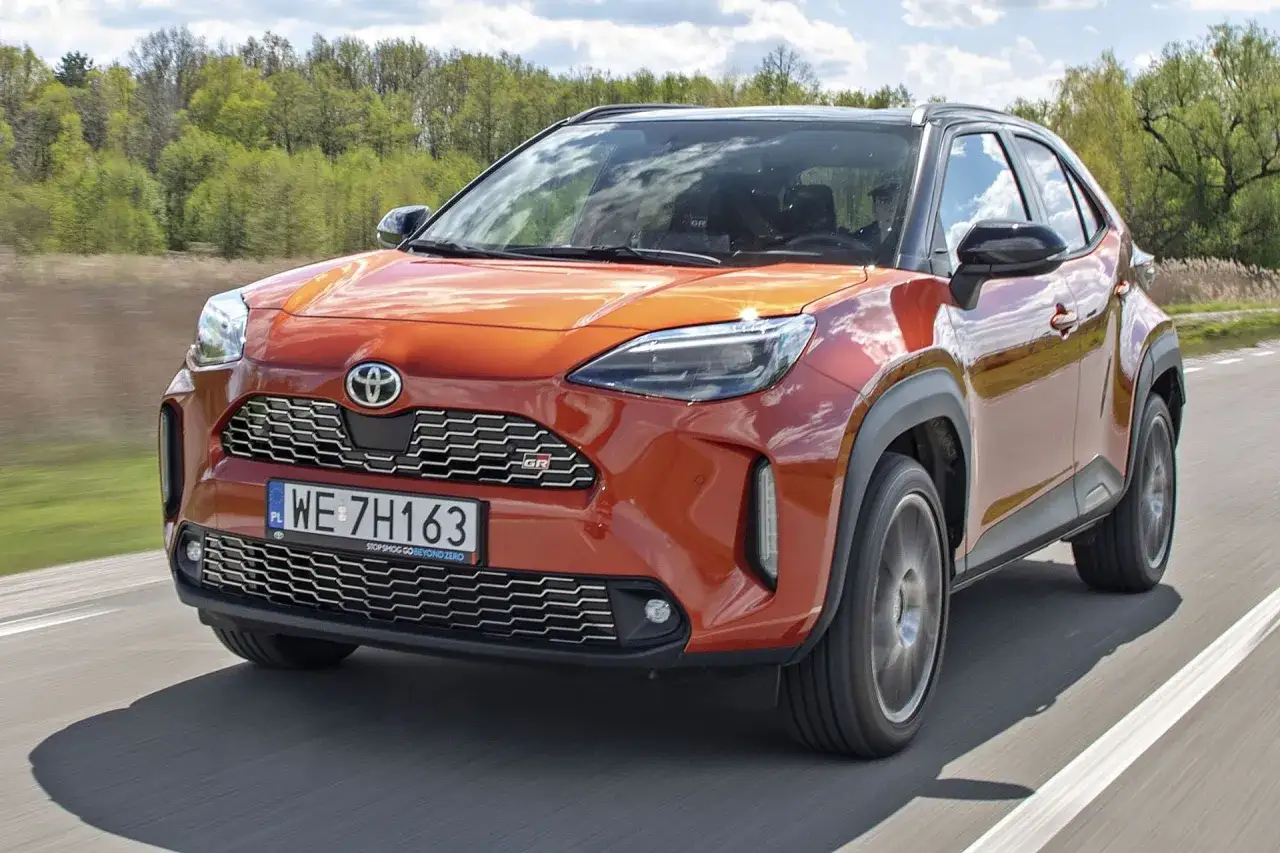 Pomarańczowy Toyota Yaris Cross GR Sport na drodze. Sprawdź atrakcyjną toyota yaris cross cena i wyposażenie.