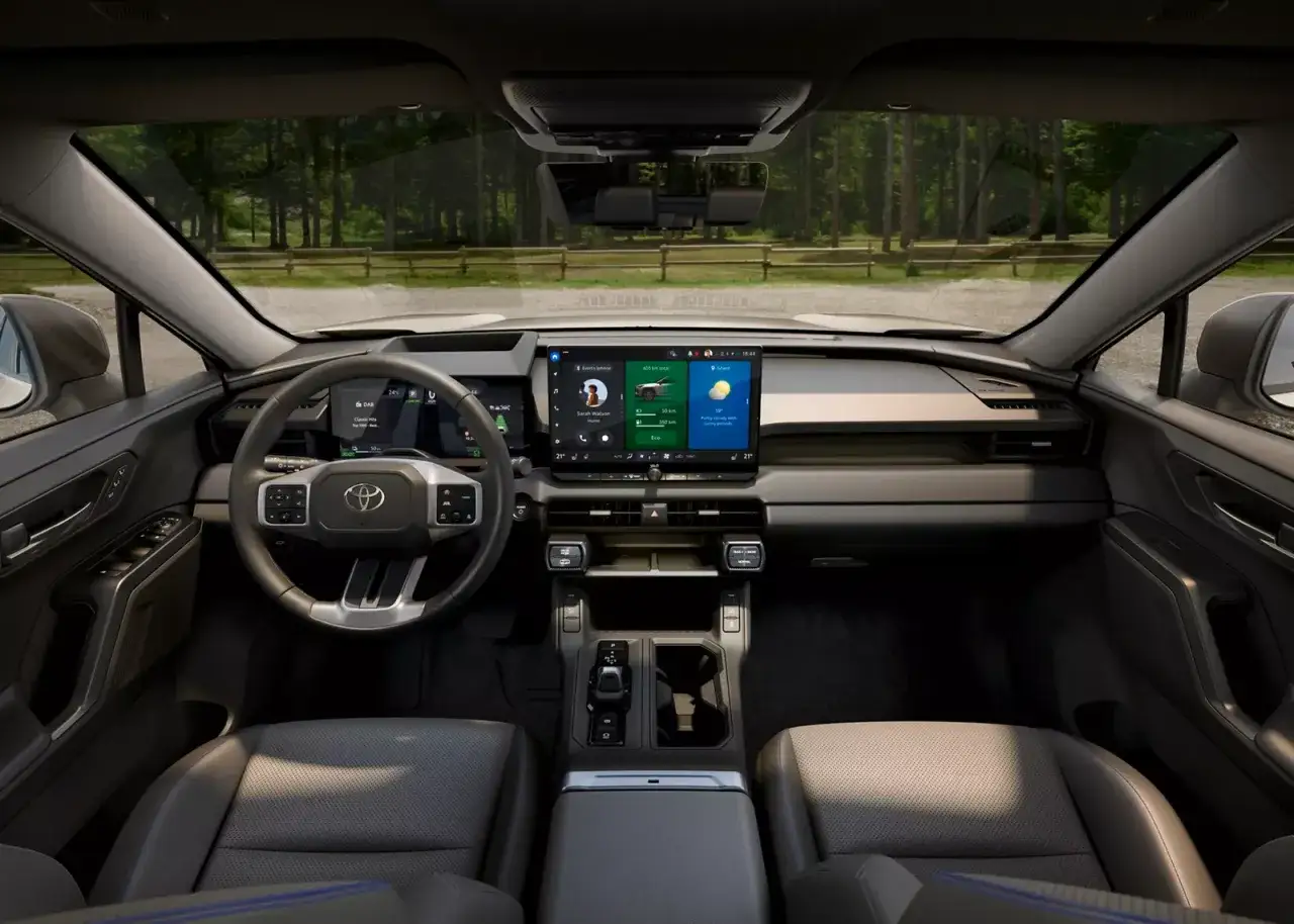 Wnętrze Toyota RAV4 2023 z nowoczesnym ekranem multimedialnym i cyfrowymi zegarami.