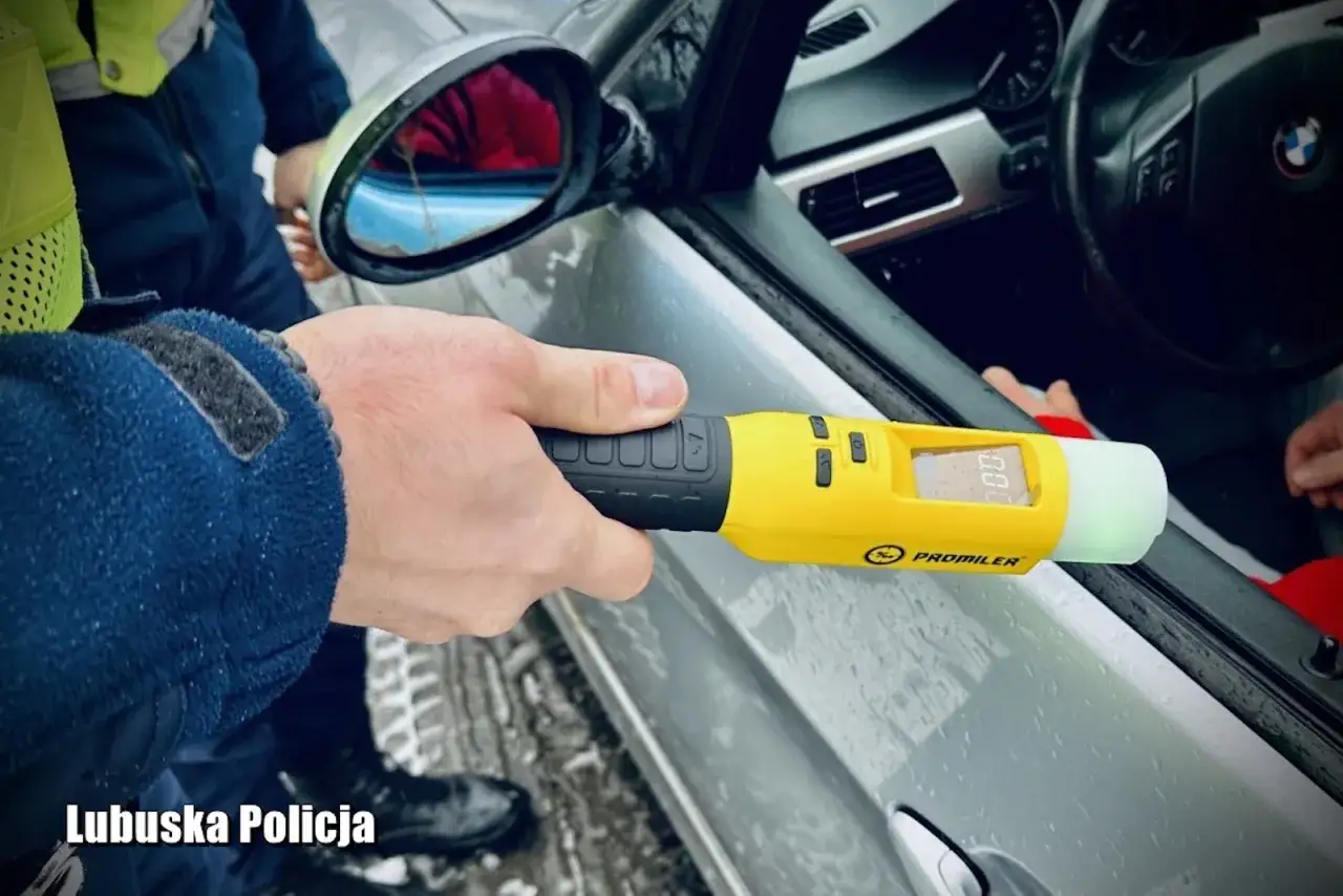 Policjant sprawdza, ile alkoholu we krwi ma kierowca. Żółty alkomat Promiler pokazuje wynik 0.00.