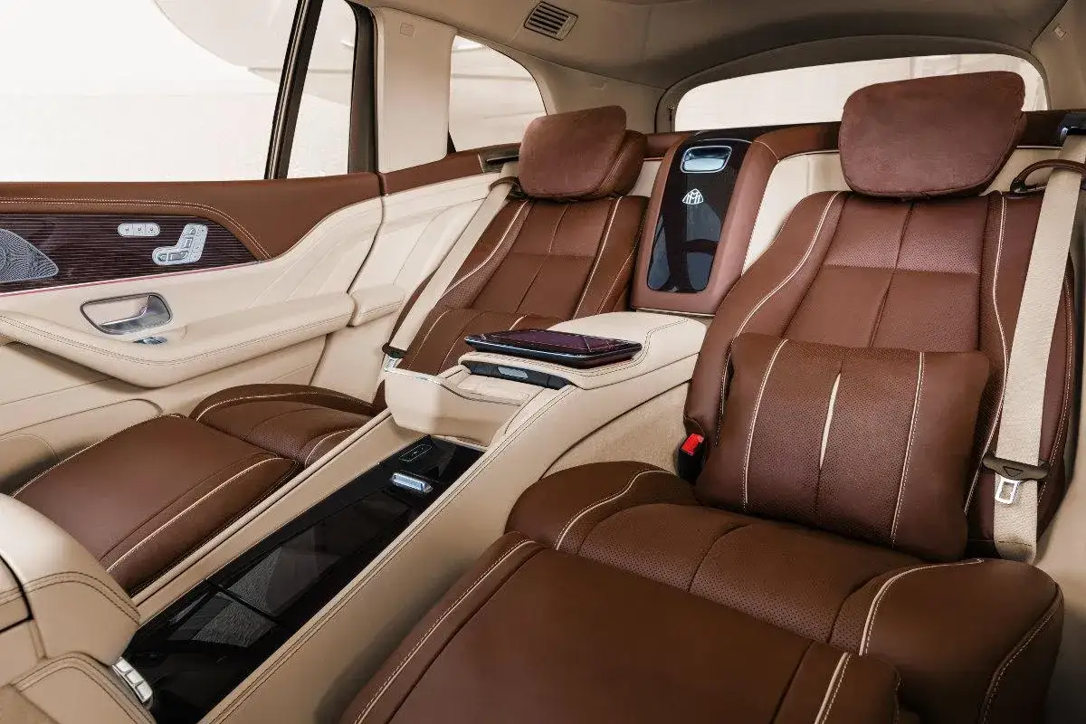 Luksusowe wnętrze Maybach GLS 600 z brązową i beżową skórzaną tapicerką, podłokietnikiem i poduszkami.