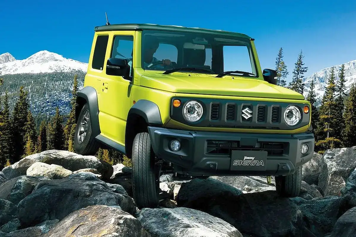 Żółty Suzuki Jimny 2026 pokonuje skalisty teren, gotowy na przygodę w górach.
