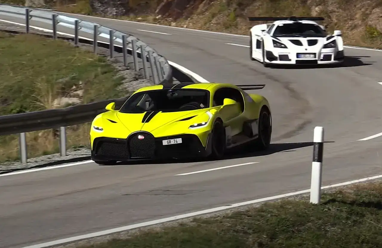 Żółty Bugatti Divo z czarnymi pasami pędzi po górskiej drodze, a za nim biały supersamochód.