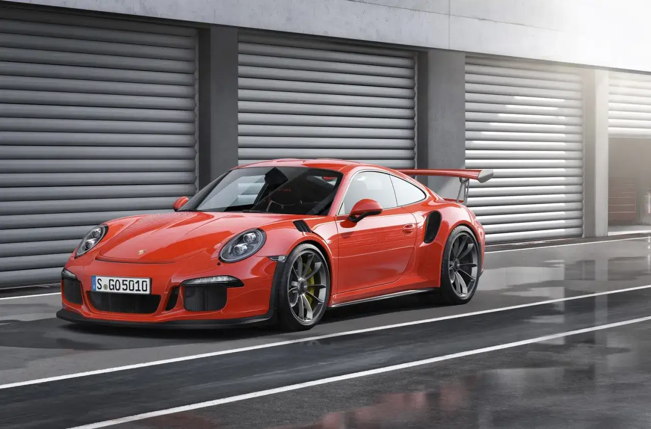 Pomarańczowy Porsche 911 GT3 RS z dużym skrzydłem, gotowy do wyścigu. Sprawdź porsche 911 gt3 rs cena.