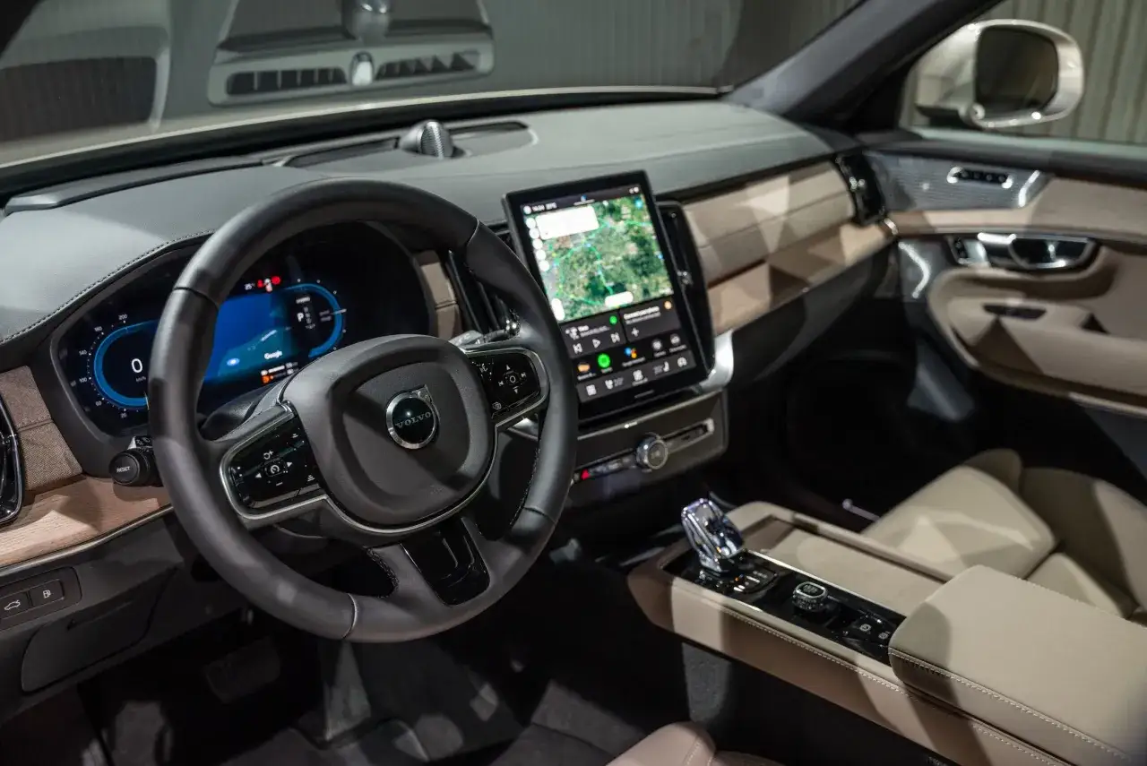 Wnętrze Volvo XC90 2025 z ekranem nawigacji i cyfrowymi zegarami.