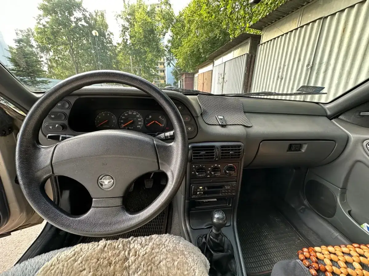 Wnętrze Daewoo Espero: kierownica, deska rozdzielcza z zegarami i radiem, dźwignia zmiany biegów. Widok z perspektywy kierowcy.