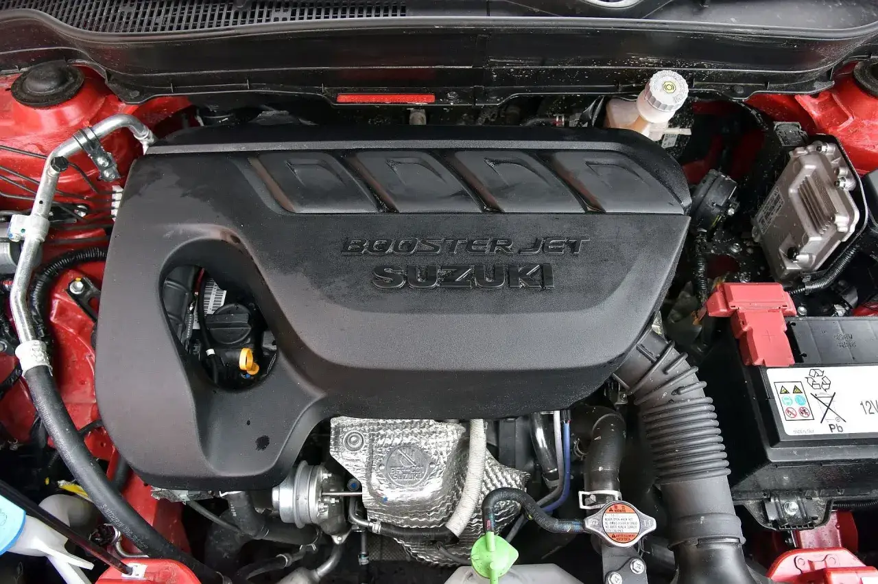 Silnik Booster Jet Suzuki w Suzuki Vitara 2023. Widoczna pokrywa silnika z logo, turbosprężarka i akumulator.