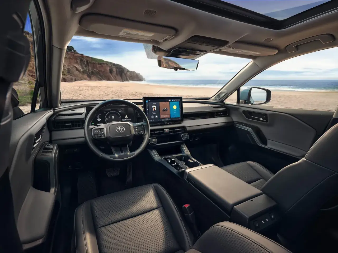 Wnętrze nowoczesnego toyota rav z widokiem na plażę i ocean. Skórzana tapicerka, duży ekran multimedialny i panoramiczny dach.