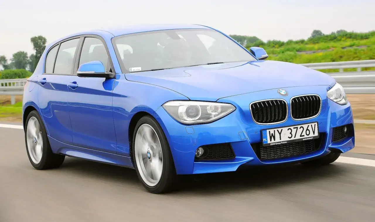 Niebieskie BMW 116i pędzi po drodze, ukazując swoje sportowe linie i dynamiczny charakter.