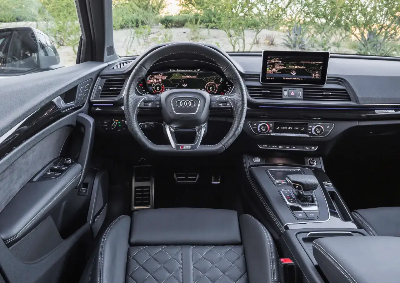 Wnętrze Audi Q5 quattro z cyfrowymi zegarami, ekranem nawigacji i skórzaną tapicerką.