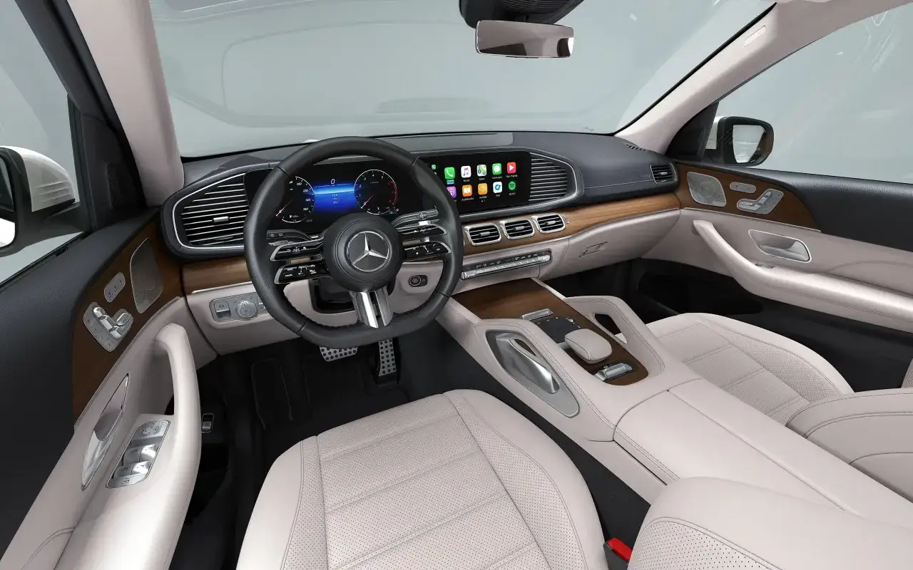 Wnętrze luksusowego Mercedesa GLS 580 z jasną tapicerką, drewnianymi wstawkami i nowoczesnym panelem multimedialnym.