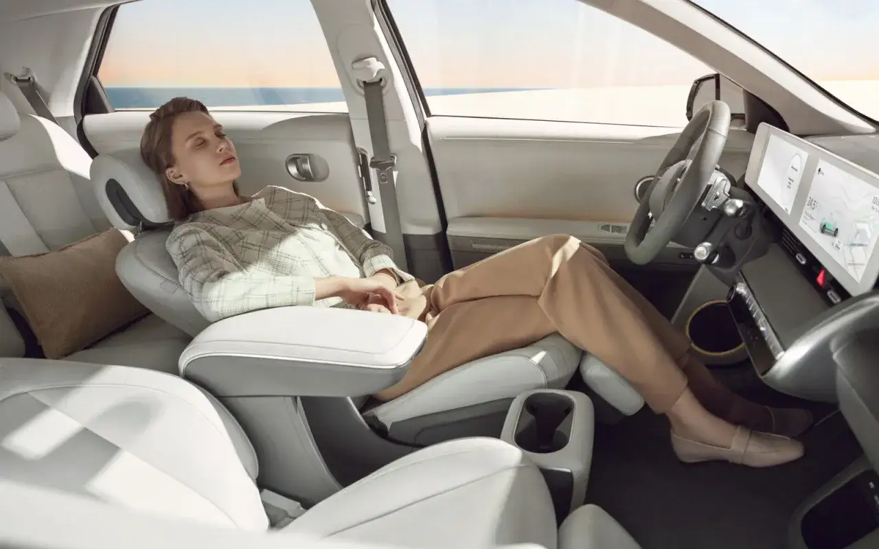 Kobieta odpoczywa w przestronnym wnętrzu Hyundai Ioniq 5, rozłożony fotel zapewnia komfort podróży.