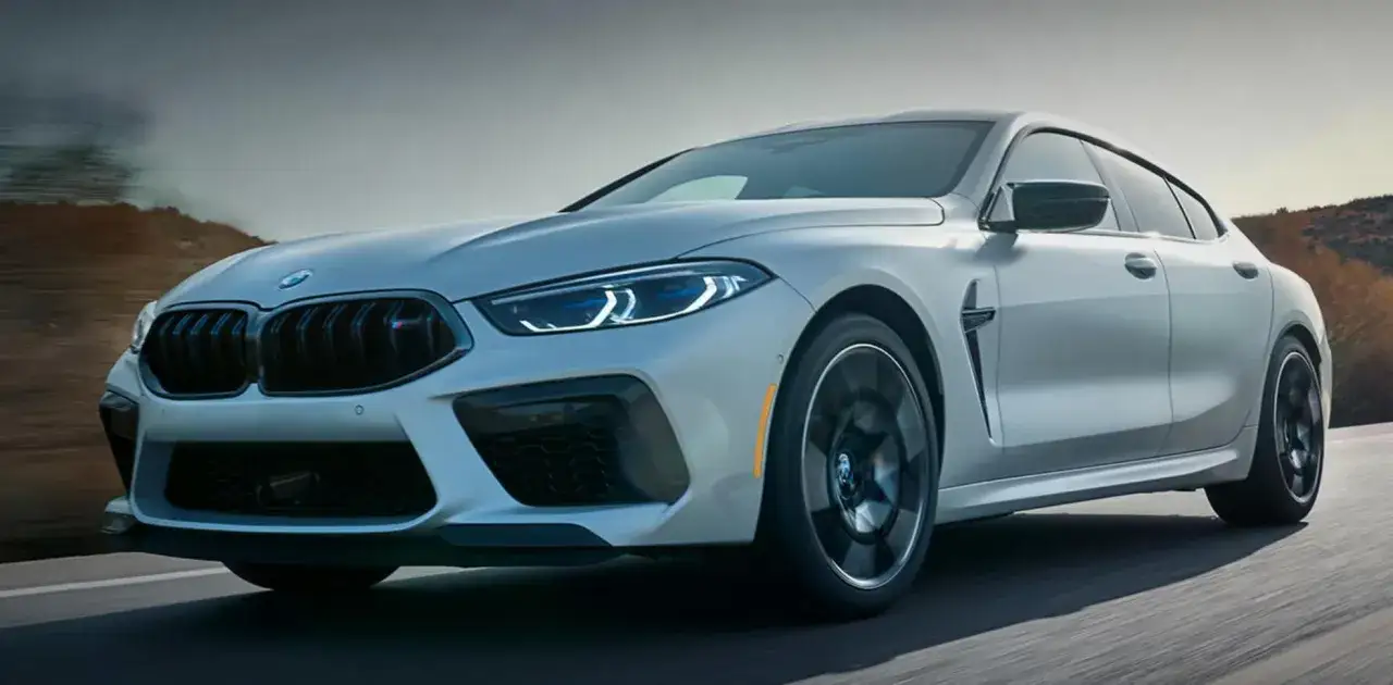 Srebrne BMW 2025 z agresywnym grillem i ostrymi światłami LED pędzi po drodze, ukazując swoją sportową sylwetkę.