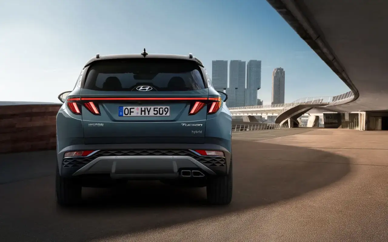 Tylna część hyundai tucson wymiary, z charakterystycznymi światłami LED i podwójnymi końcówkami wydechu, na tle nowoczesnej architektury miejskiej.