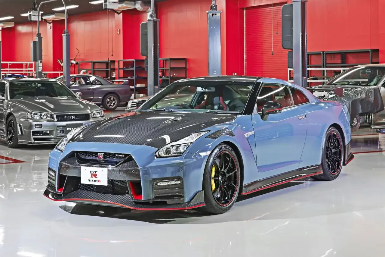 Niebieski Nissan GT-R Nismo z karbonową maską i czerwonymi akcentami, obok szarego Nissana GT-R R34.