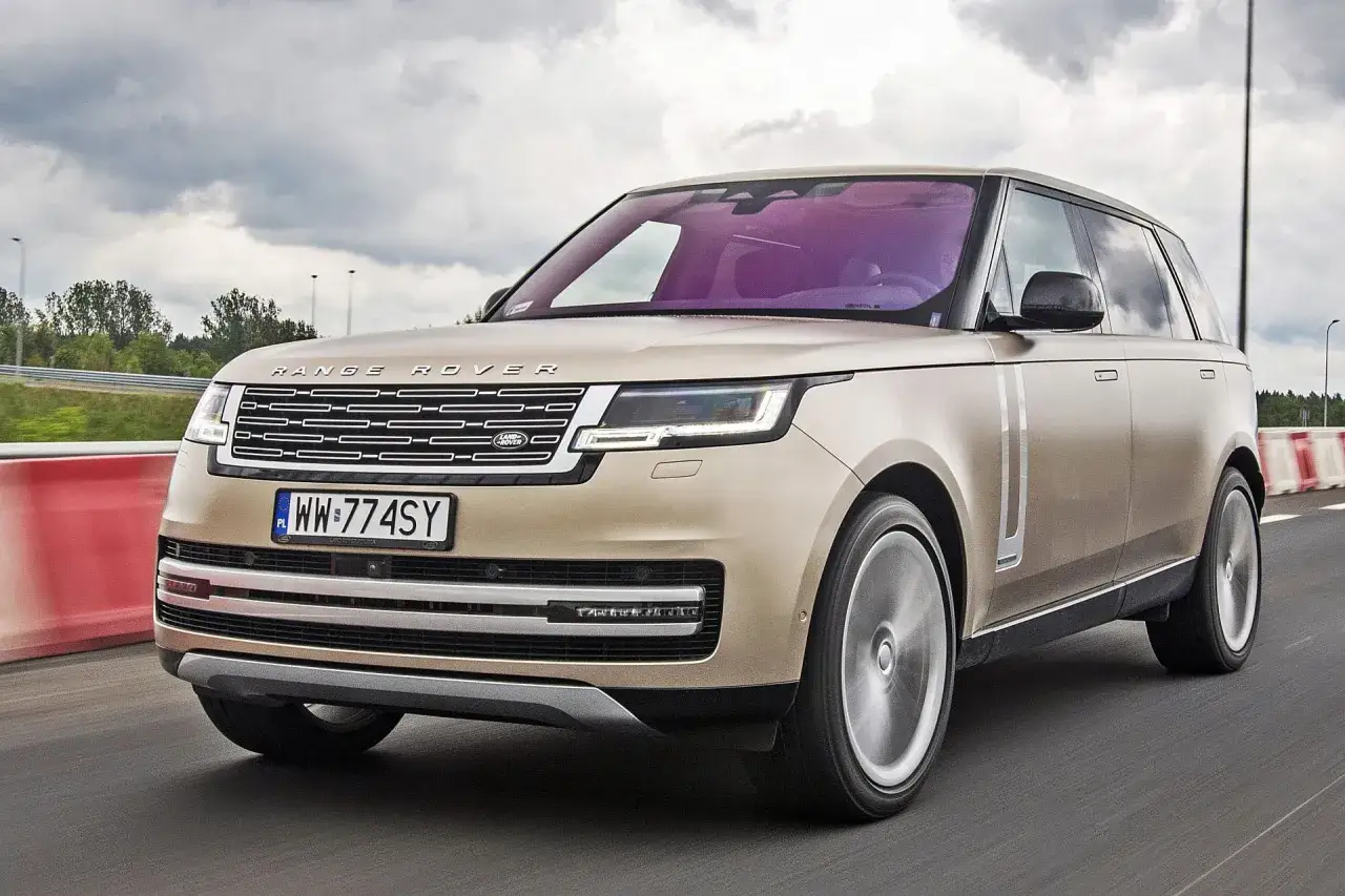 Elegancki, beżowy Range Rover 2025 pędzi po drodze, jego felgi wirują w ruchu.
