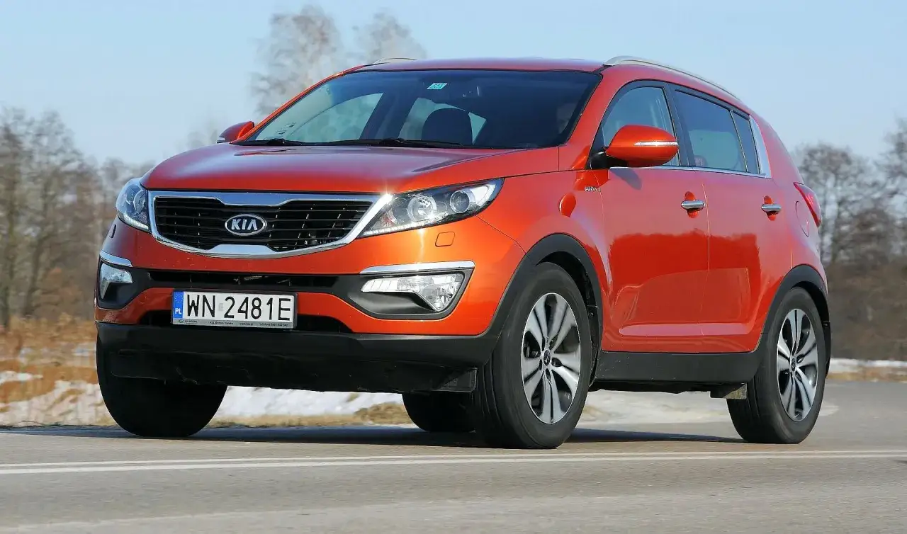 Pomarańczowy Kia Sportage 2015 na drodze, z widocznym numerem rejestracyjnym WN 2481E.