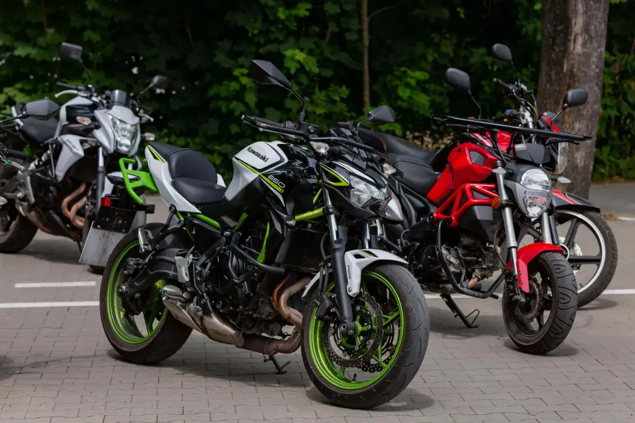 Trzy motocykle: biało-czarny Kawasaki z zielonymi akcentami, czerwony i biały. Idealne dla posiadaczy prawa jazdy A2.
