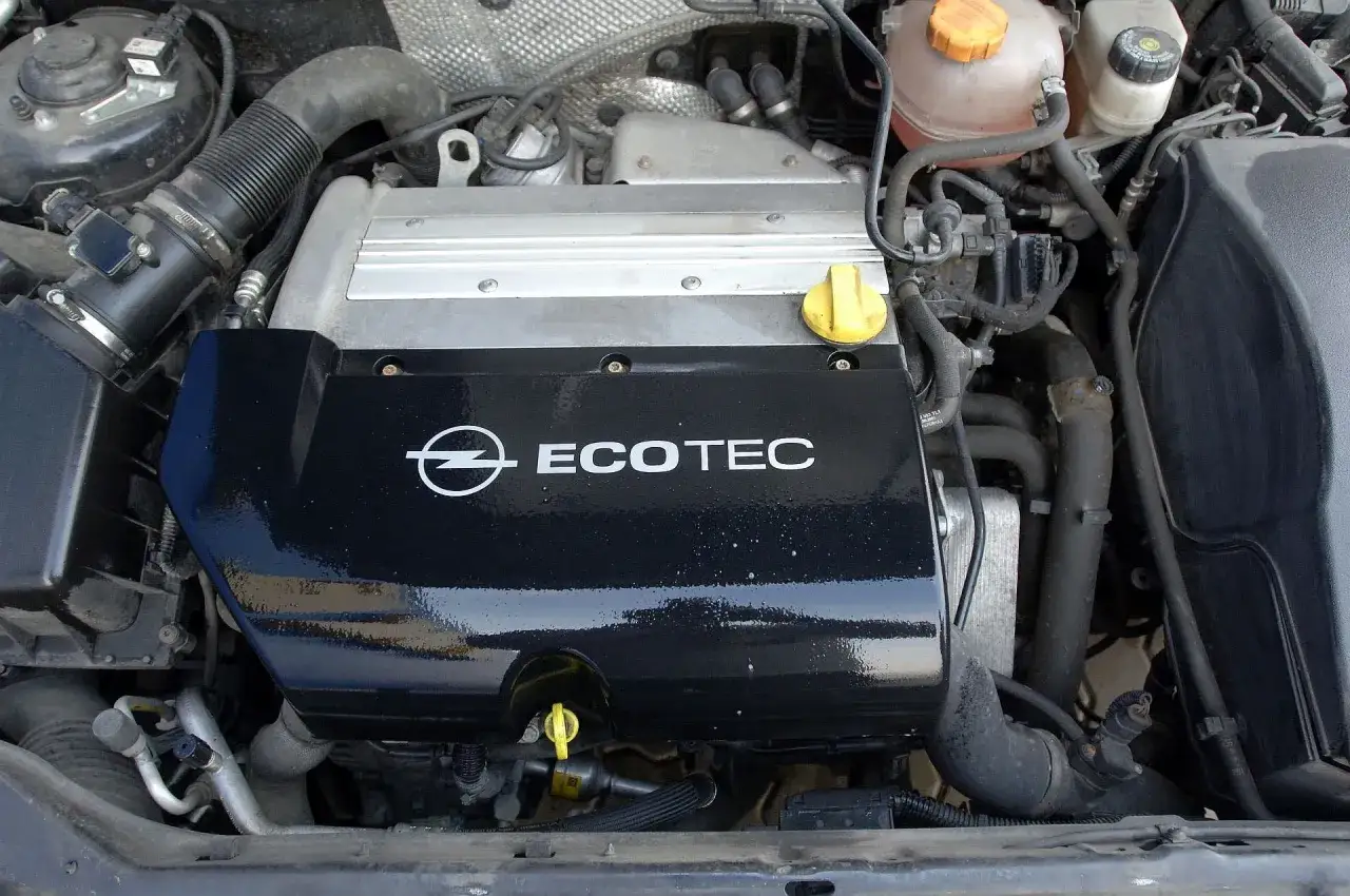 Silnik Ecotec w Oplu Vectra C, jaki silnik najmniej awaryjny? Widok na czarną pokrywę silnika z logo Opel i napisem Ecotec.