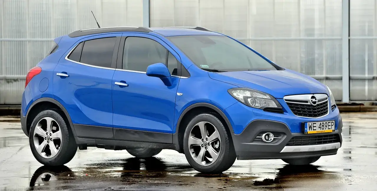 Niebieski Opel Mokka, idealny SUV do 30 tys. zł, stoi na mokrej nawierzchni.