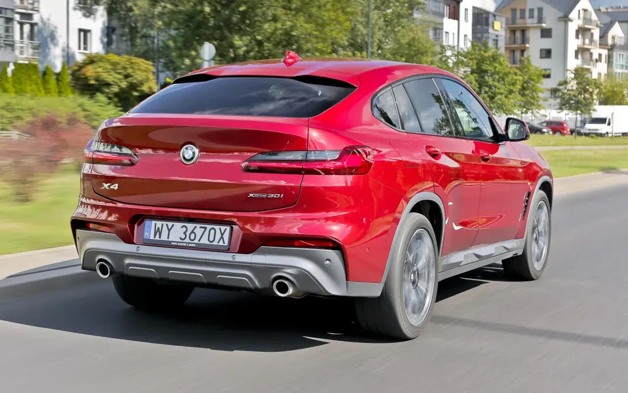 Czerwone BMW X4 2025 w ruchu, z widocznym tyłem i tablicą rejestracyjną.