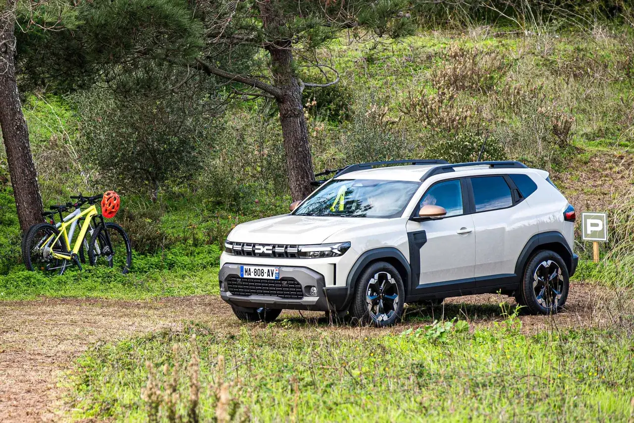 Biały Dacia Duster 1.6 benzyna zaparkowany w lesie obok rowerów.
